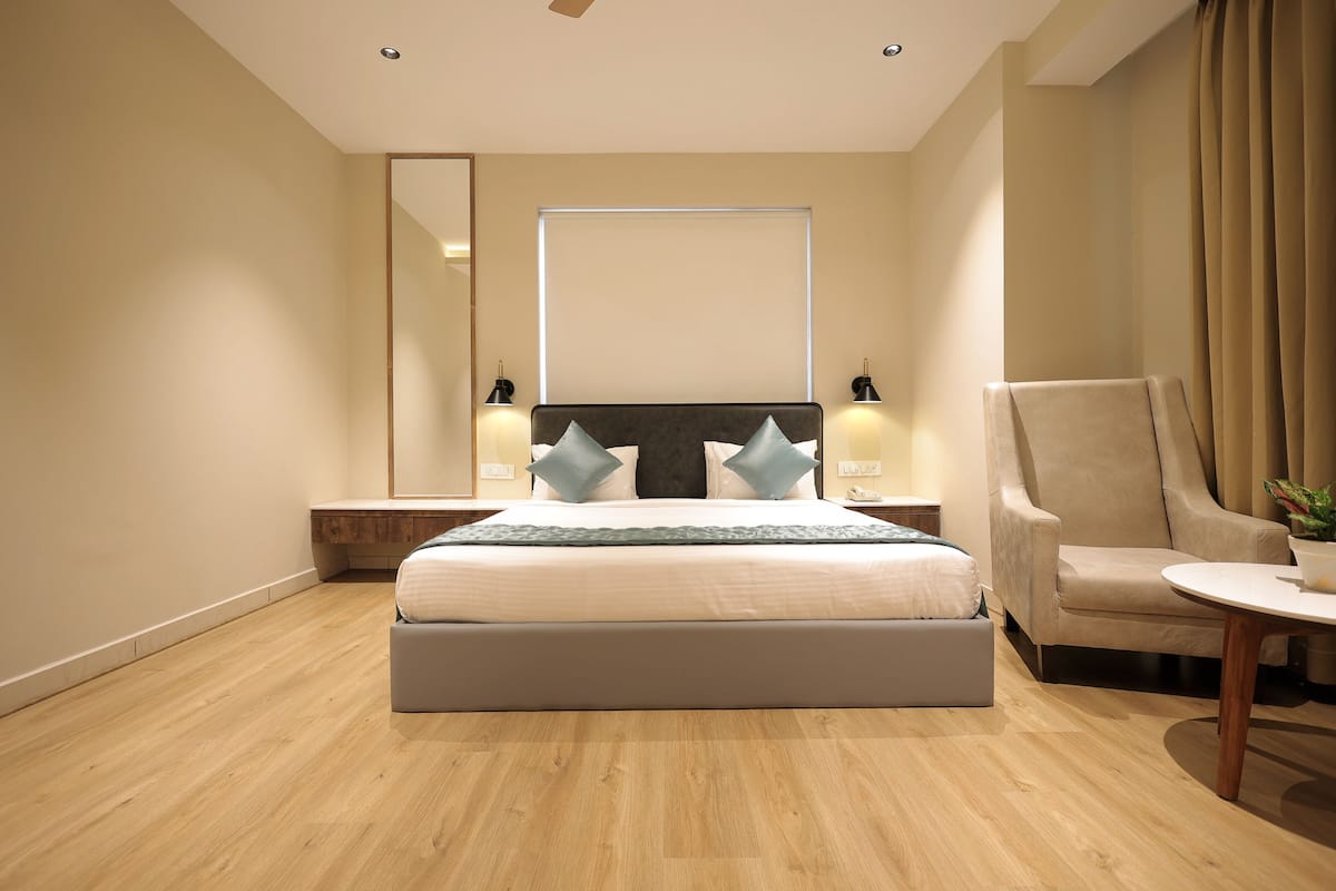 Una habitación de hotel moderna con una cama grande, una silla, una mesita y un espejo.