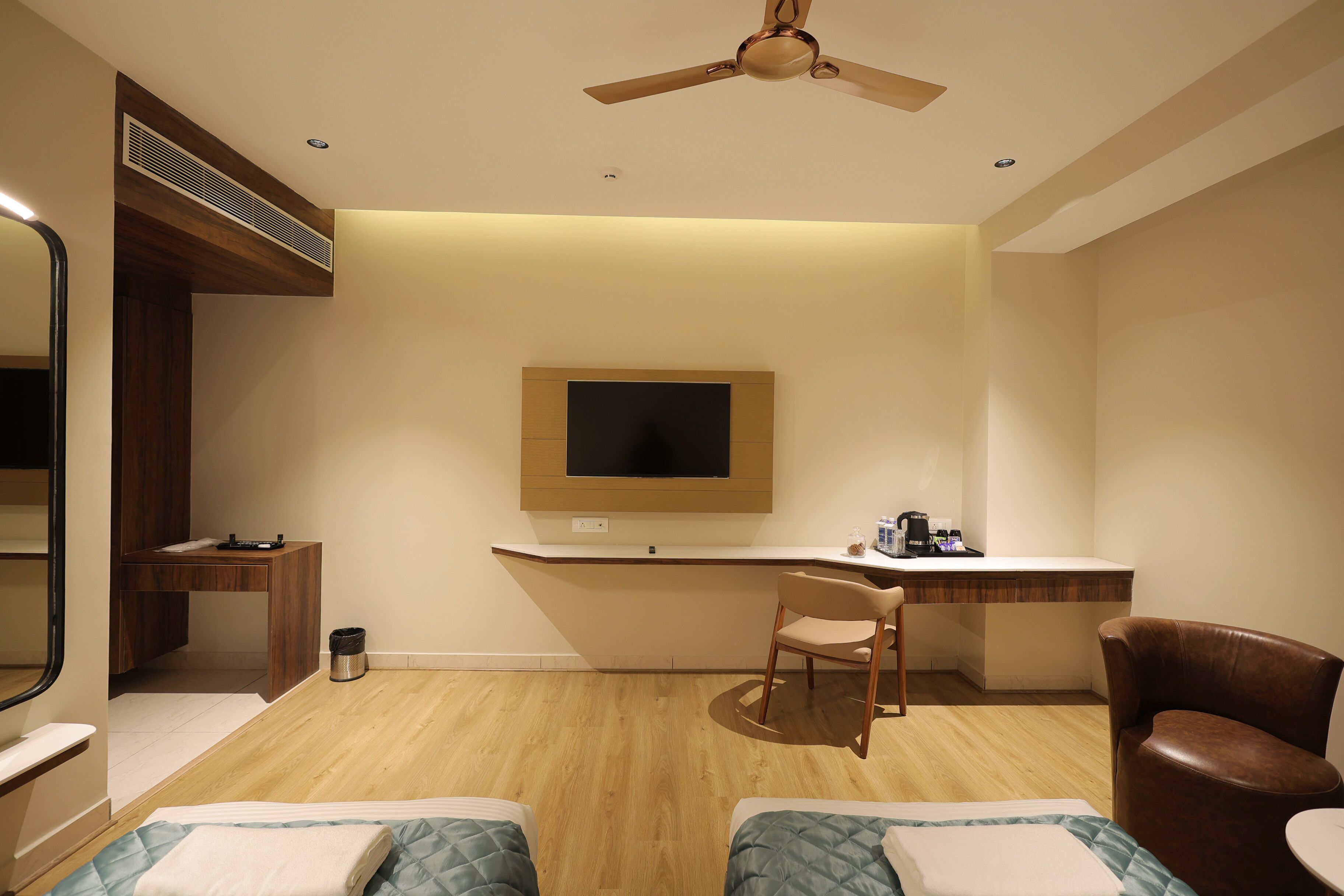 Une chambre d’hôtel équipée d’un lit, d’un bureau, d’une chaise, d’une télévision et d’un ventilateur de plafond.