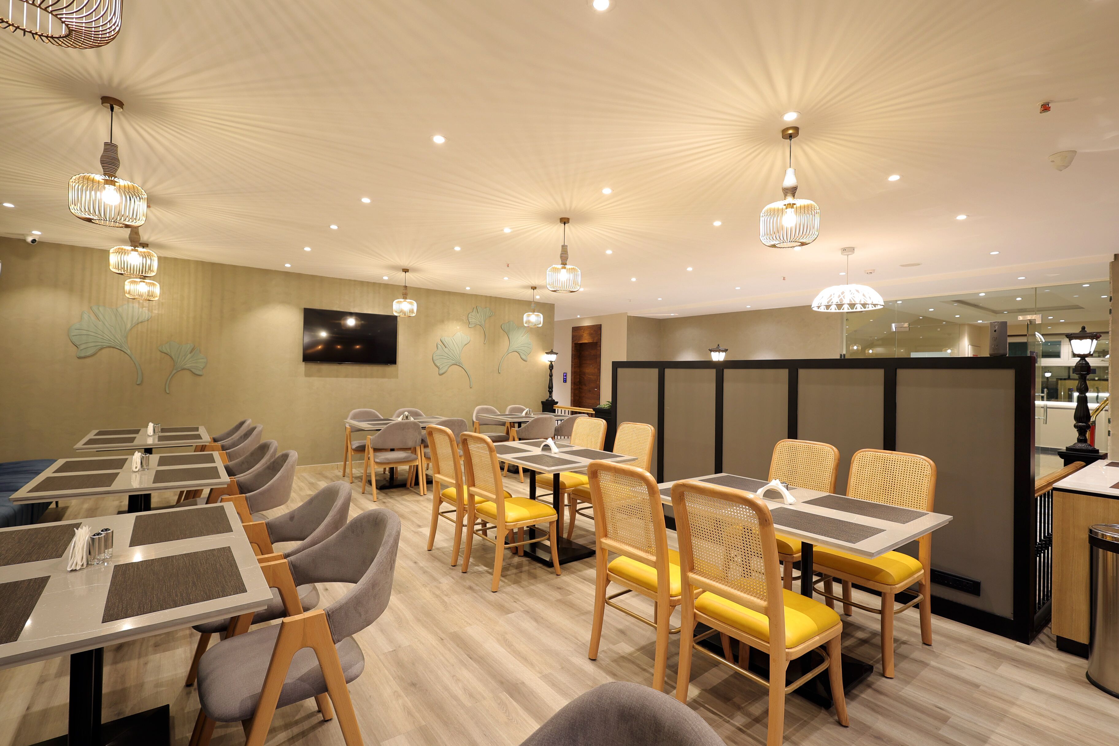 Un ristorante con diversi tavoli e sedie, un design moderno del soffitto e opere d'arte alle pareti.