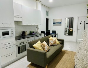 Una cocina moderna con armarios blancos, horno integrado y comedor con mesa y sillas.