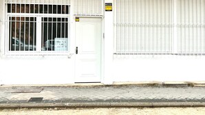 A building facade with a white door, barred windows, and a sign indicating a residential use. - Apartamento Huerta del Convento (Madrid)