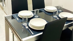 A dining table set with plates, glasses, and cutlery in a modern kitchen. - Apartamento Huerta del Convento (Madrid)