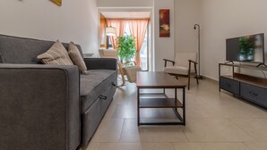 A modern living room with a grey sofa, a wooden coffee table, and a TV on a stand.