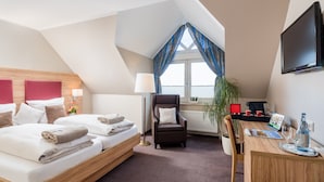 A hotel room with a bed, a desk, a chair, a TV, and a window with curtains. - Hotel Stadtidyll (Rotenburg)