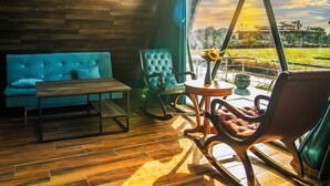 A modern interior with a teal sofa, a rocking chair, and a wooden table. - Sunflower Saga (Jamwa Ramgarh)