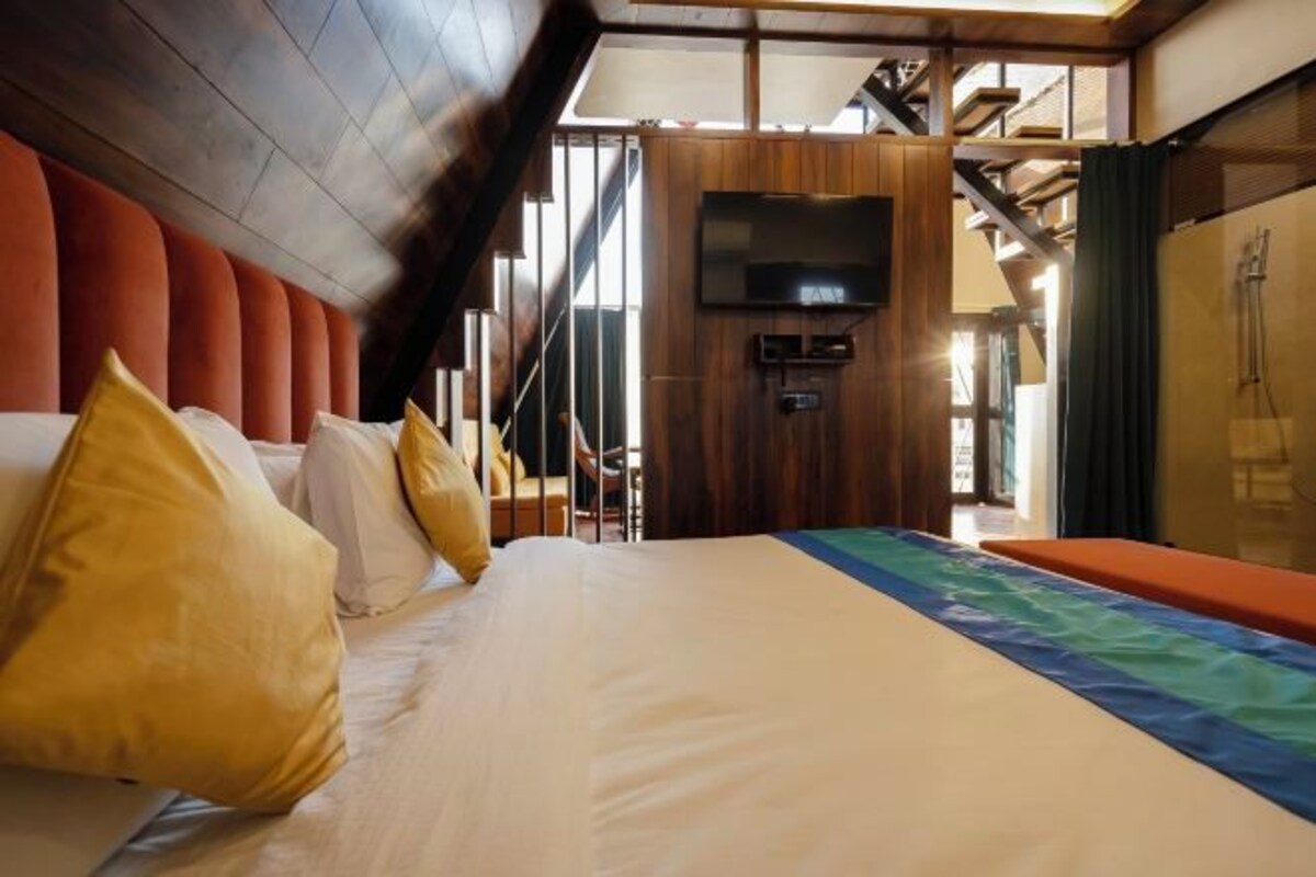 A hotel room with a bed, wooden paneling, a television, and a view of the outdoors.
