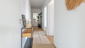 Een gang met een spiegel, een lijst met een afbeelding en een wandkleed.