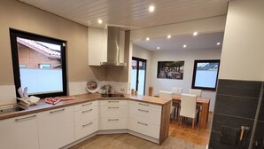 Una cocina moderna con armarios blancos, encimera de madera y estufa integrada.