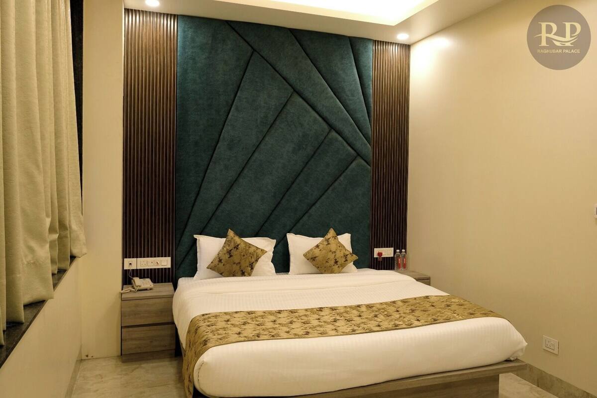 Habitación de hotel con una cama grande, cabecera con diseño geométrico y mesita de noche con un teléfono y una botella.
