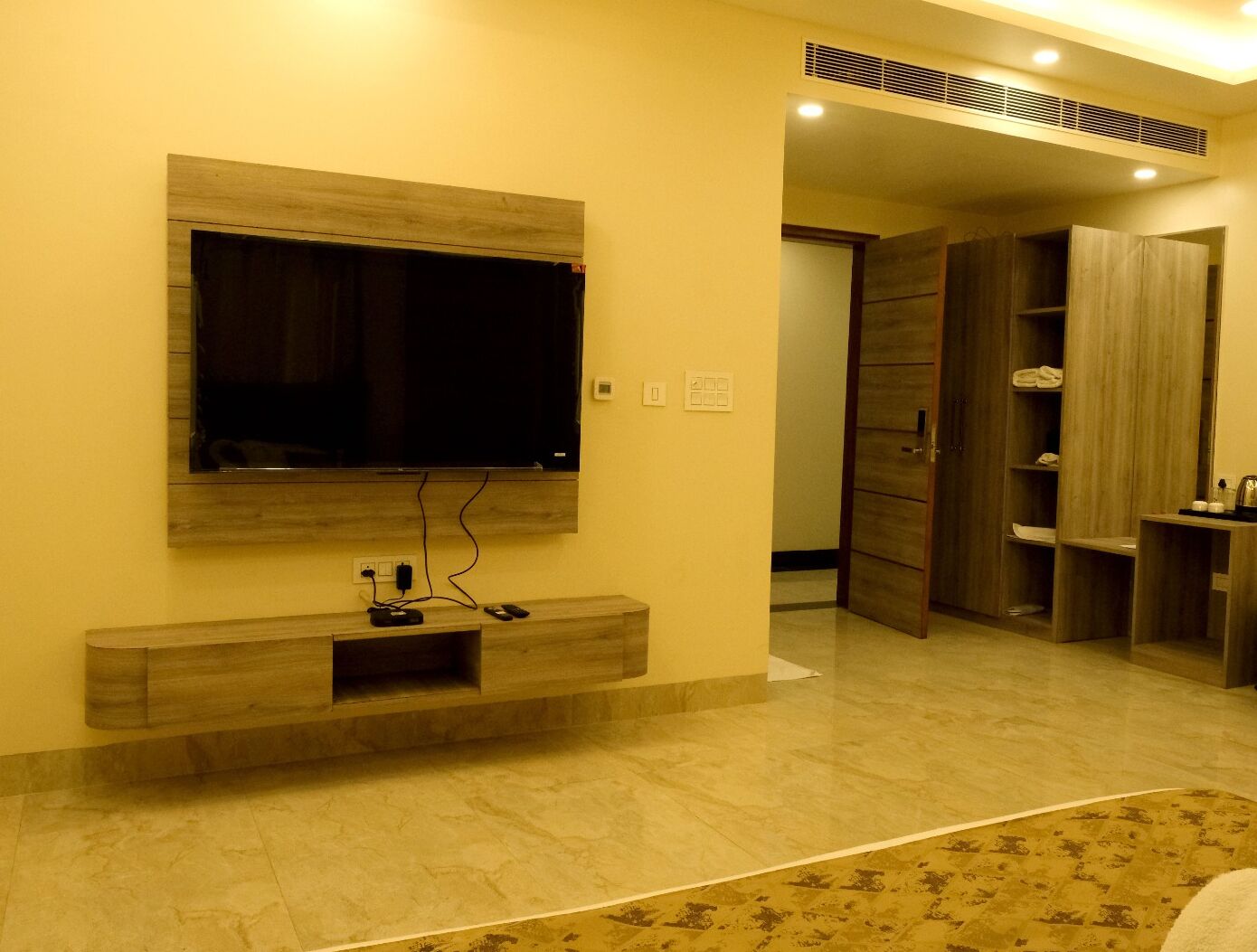 Una sala de estar moderna con un televisor de pantalla plana montado en una pared de madera, un mueble de entretenimiento empotrado debajo y un armario de madera a la derecha.