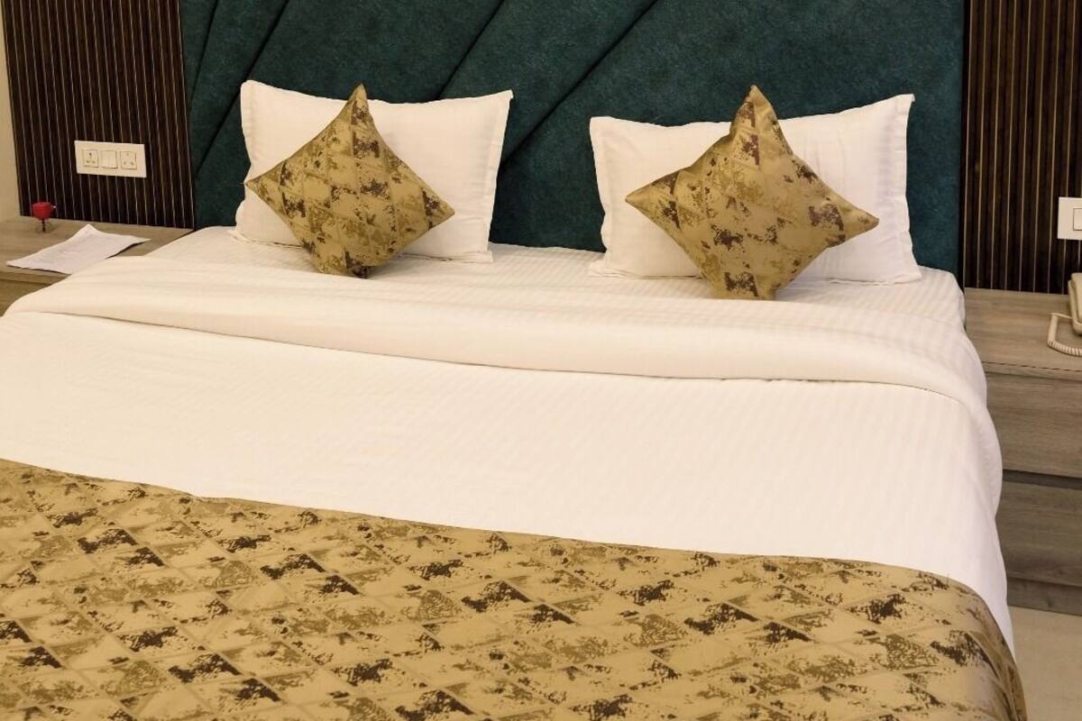 Una cama con colcha estampada, dos almohadas decorativas y un cabecero texturizado.