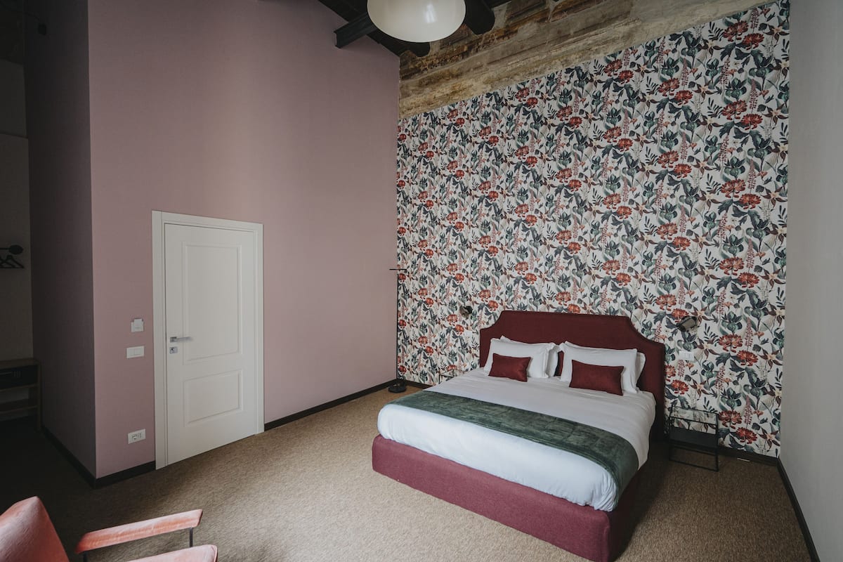 Ein Schlafzimmer mit einem Bett, einer Tür und Blumenmuster-Tapete.
