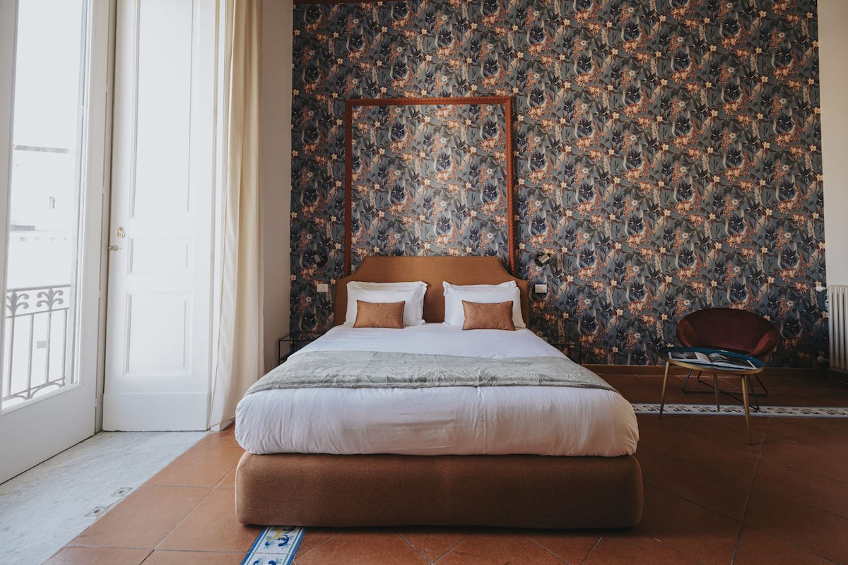 Ein Schlafzimmer mit einem großen Bett, einem Sessel und einer Wand mit Muster.