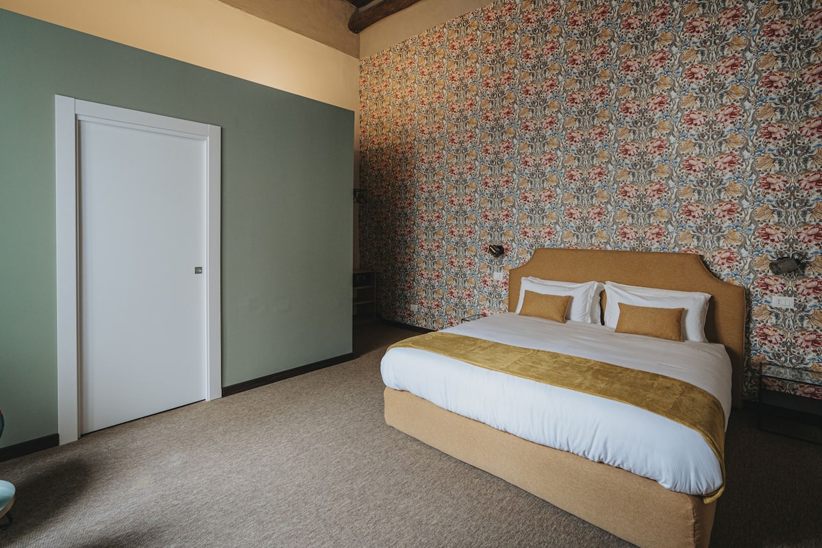 Ein Schlafzimmer mit einem Bett, einer Tür und einer Wand mit floralem Wandpapier.