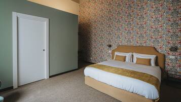 A bedroom with a bed, a door, and a floral wallpapered wall.