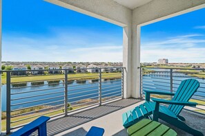 A balcony with a view of a river, a row of houses, and a distant building. - Fun 2BR Retreat! Theme Room, Lake View near Disney (Kissimmee)