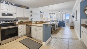 A modern kitchen with white cabinets, a built-in microwave, and a large island with seating.
