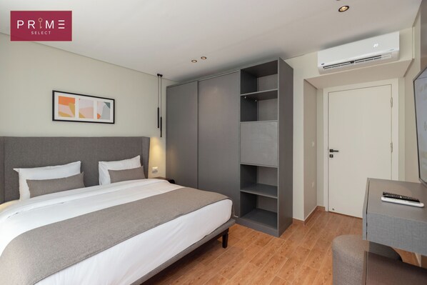 A modern hotel room with a bed, wardrobe, and desk area.