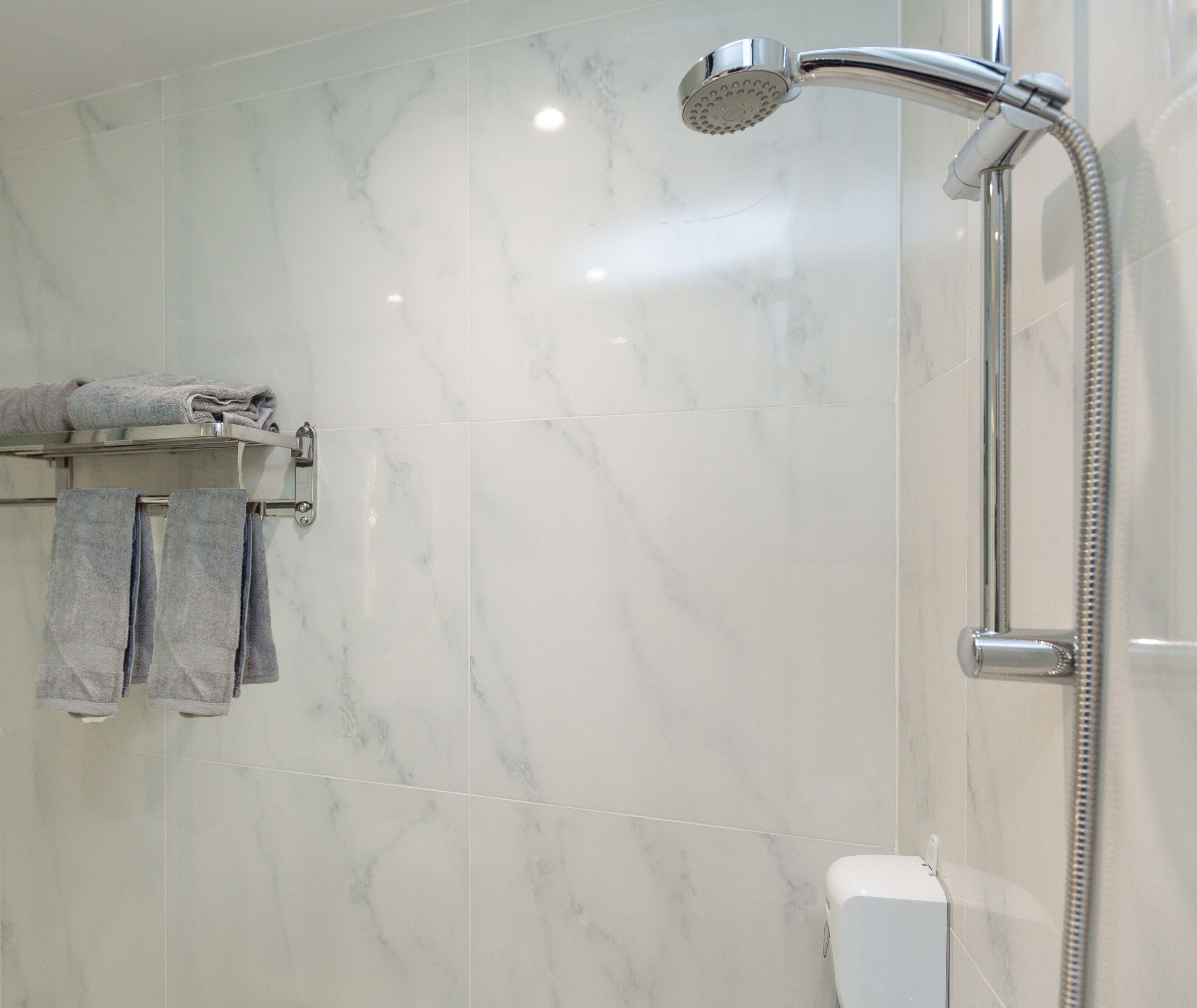 A bathroom with a shower, a towel rack with towels, and a toilet.