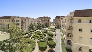 Un ensemble résidentiel comprenant plusieurs immeubles d’appartements, un espace paysager central agrémenté d’un kiosque et un ciel dégagé.