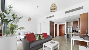 Un salon moderne avec un canapé gris, une table basse blanche et un coin repas comprenant une table et des chaises blanches.
