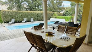 An outdoor patio with a pool, lounge chairs, a table with chairs, and a barbecue grill. - Maison Familial, Piscine Privée, à 5mins des Plages de Santa-guilia, Palombaggia (Porto-Vecchio)