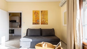 Una sala de estar con un sofá, una mesa de centro y dos cuadros en la pared.