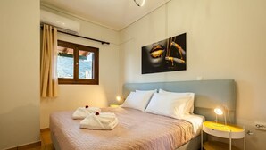 Una habitación de hotel con una cama, una mesita de noche con lámpara, una ventana con cortinas y un cuadro en la pared.