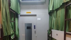 Um corredor estreito com cortinas verdes, uma porta de empurrar e um aparelho de ar condicionado em cima.
