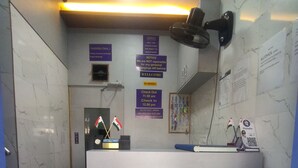 Uma área de recepção com piso de mármore, um balcão de recepção identificado com 'RECEPTION' e várias placas, incluindo 'PROIBIDO FUMAR' e 'Saída às 11:00'.