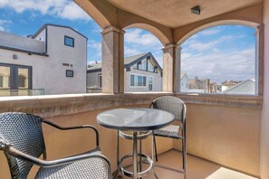 Ein Balkon mit rundem Tisch und zwei Stühlen, mit Blick auf angrenzende Gebäude.