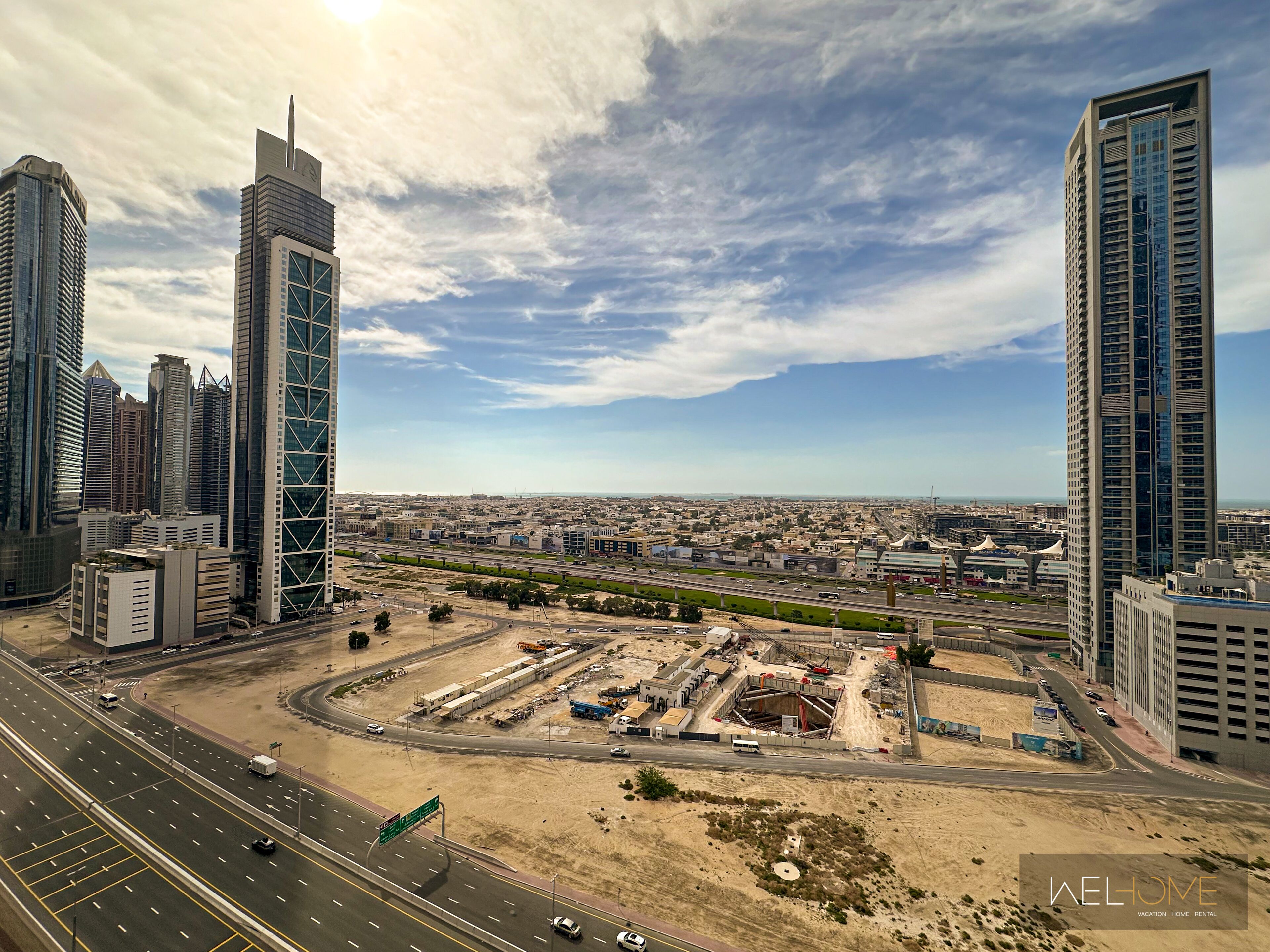 A cityscape with modern high-rise buildings, a highway, and construction sites.