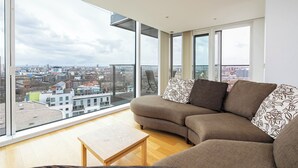Ein modernes Wohnzimmer mit einem großen Fenster, einem braunen Sofa und einem Couchtisch aus Holz.