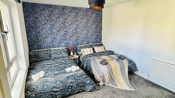 A bedroom with a large bed, a side table, and a patterned wall.