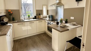 Una cocina moderna con armarios blancos, una isla central y un ventanal que proporciona luz natural.