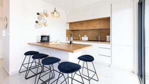 A modern kitchen with a wooden island, bar stools, a microwave, and a hanging light fixture. - Apartment Simo- stylish two bedroom apartment (Okrug Gornji)