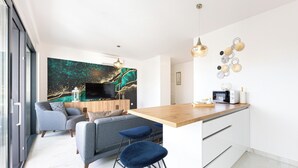 A modern kitchen with a wooden countertop, a built-in microwave, and a small dining area with a blue bar stool. - Apartment Simo- stylish two bedroom apartment (Okrug Gornji)