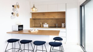 A modern kitchen with a wooden countertop, white cabinets, a built-in oven, and four bar stools. - Apartment Simo- stylish two bedroom apartment (Okrug Gornji)