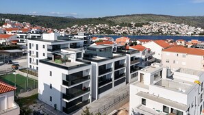 A modern residential area with multi-story buildings, balconies, and a view of a coastal town. - Apartment Simo- stylish two bedroom apartment (Okrug Gornji)