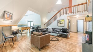 Un espacio habitable amplio con piso de madera, un sofá, una mesa de centro y una escalera.