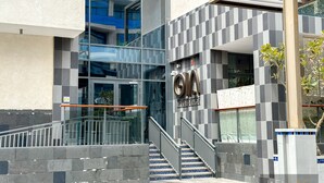 A modern building with a glass facade, a staircase with blue-tiled steps, and a sign that reads "OM Residence". - WelHome - Prime 1BR Apartment at Oia Residence (Dubai)