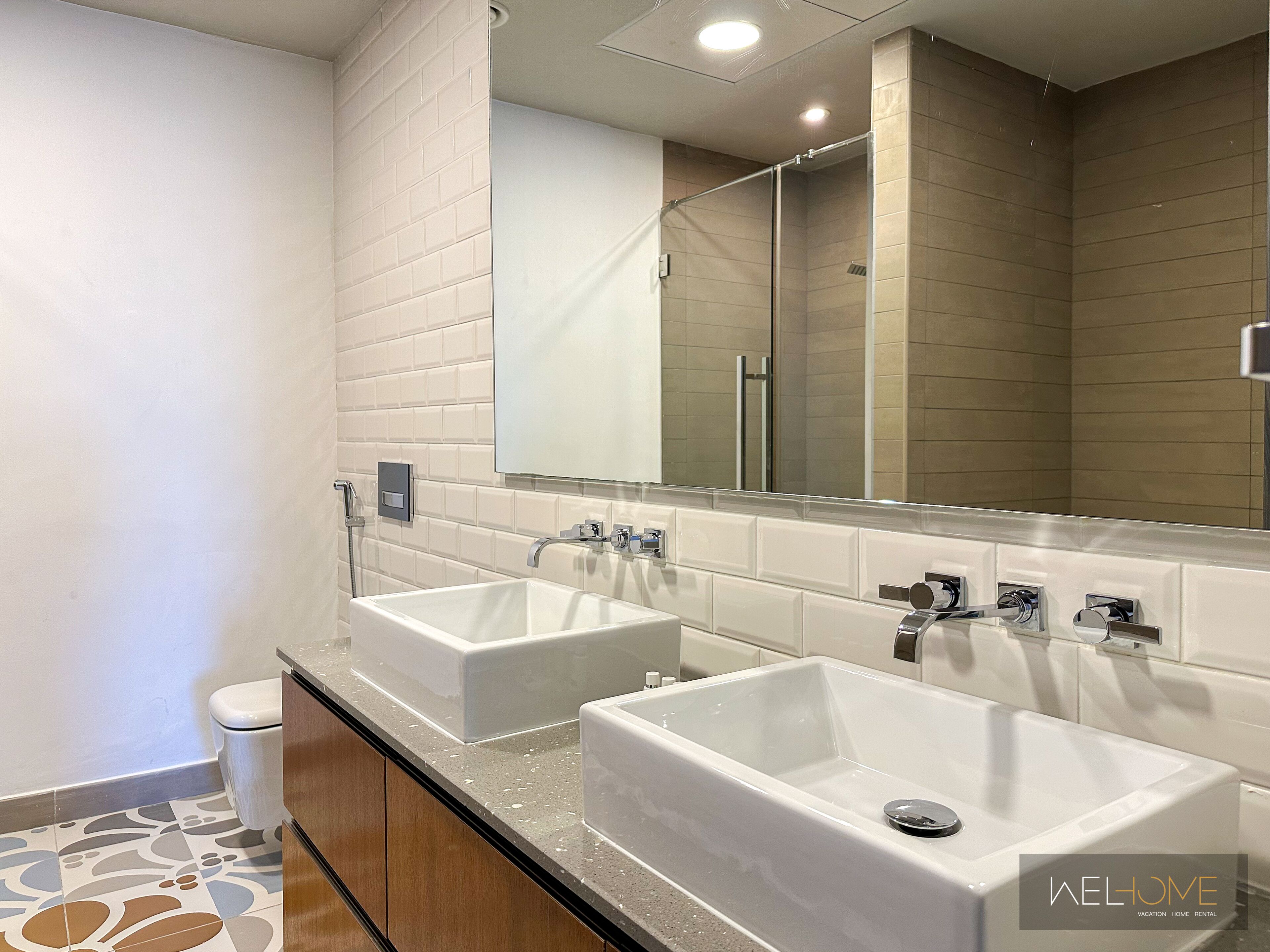 A modern bathroom with two sinks, a toilet, and a shower.