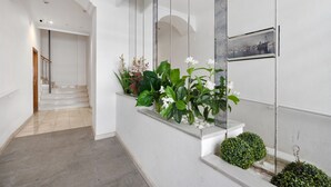 A modern hallway with a staircase, white walls, and decorative plants. - 150m from the beach, 3-bedroom apartment with nice living room and office area (Torrevieja)