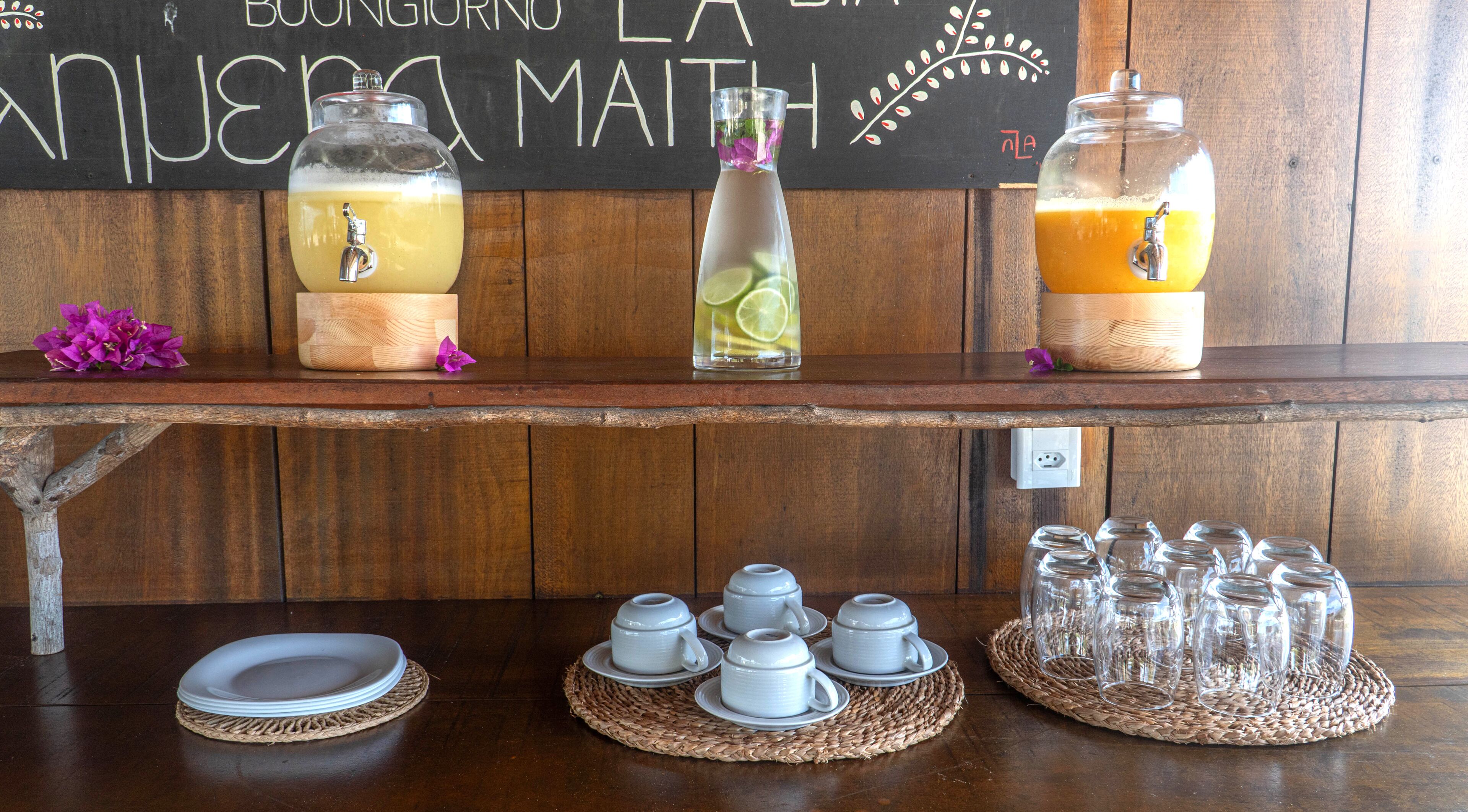 A bar area with a chalkboard menu, a beverage dispenser, and a selection of glasses and teacups.