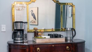 A dark wooden dresser with a mirror, a coffee maker, a kettle, and a tray with decorative items.