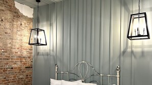 Ein Schlafzimmer mit einem großen Bett, einer Ziegelwand und einer Decke mit freiliegenden Balken.
