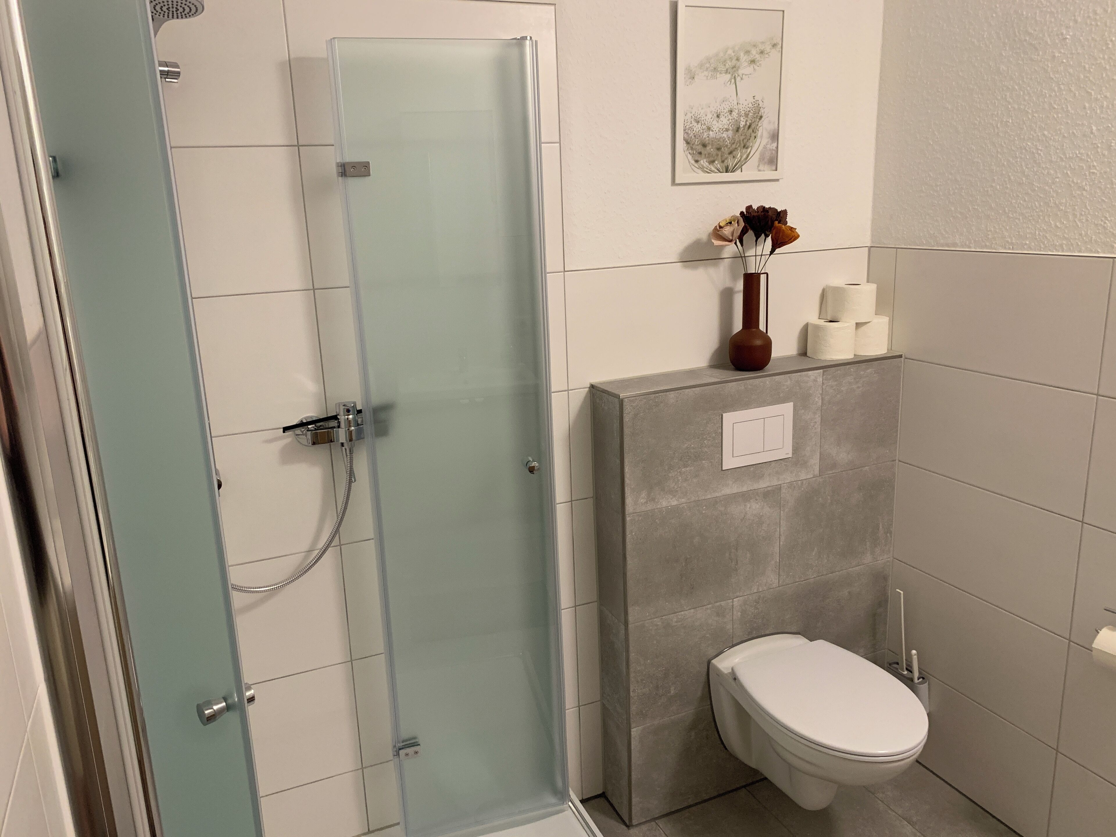 A bathroom with a glass shower enclosure, a toilet, and a wall-mounted sink.