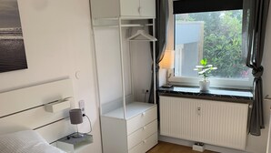 A bedroom with a bed, a dresser, a radiator, and a window with curtains. - Modernes Zentrumsnahes Apartment (Oldenburg)