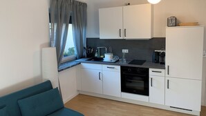 A compact kitchen with white cabinets, a built-in oven, and a coffee machine. - Modernes Zentrumsnahes Apartment (Oldenburg)