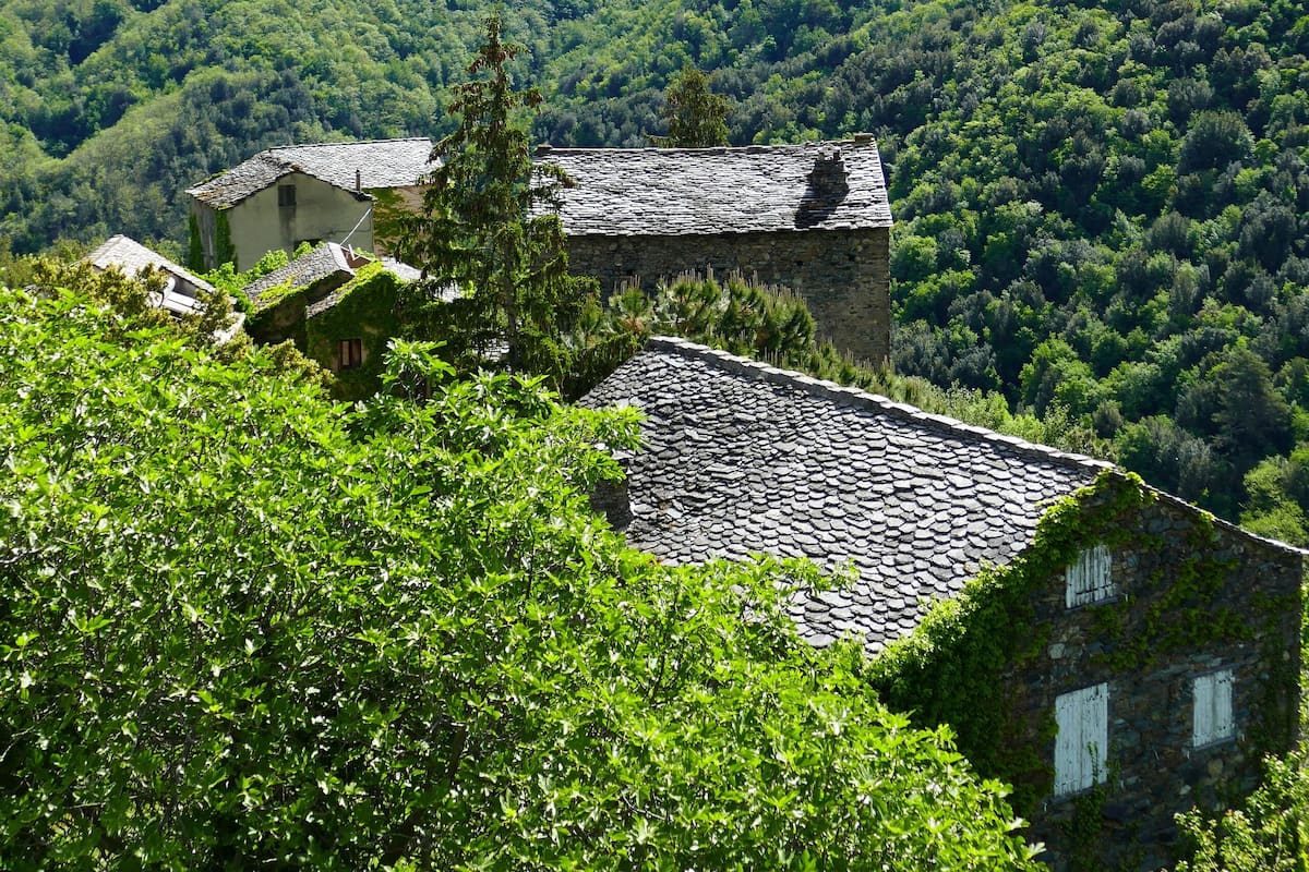 A mountainous landscape with traditional stone buildings surrounded by lush greenery.